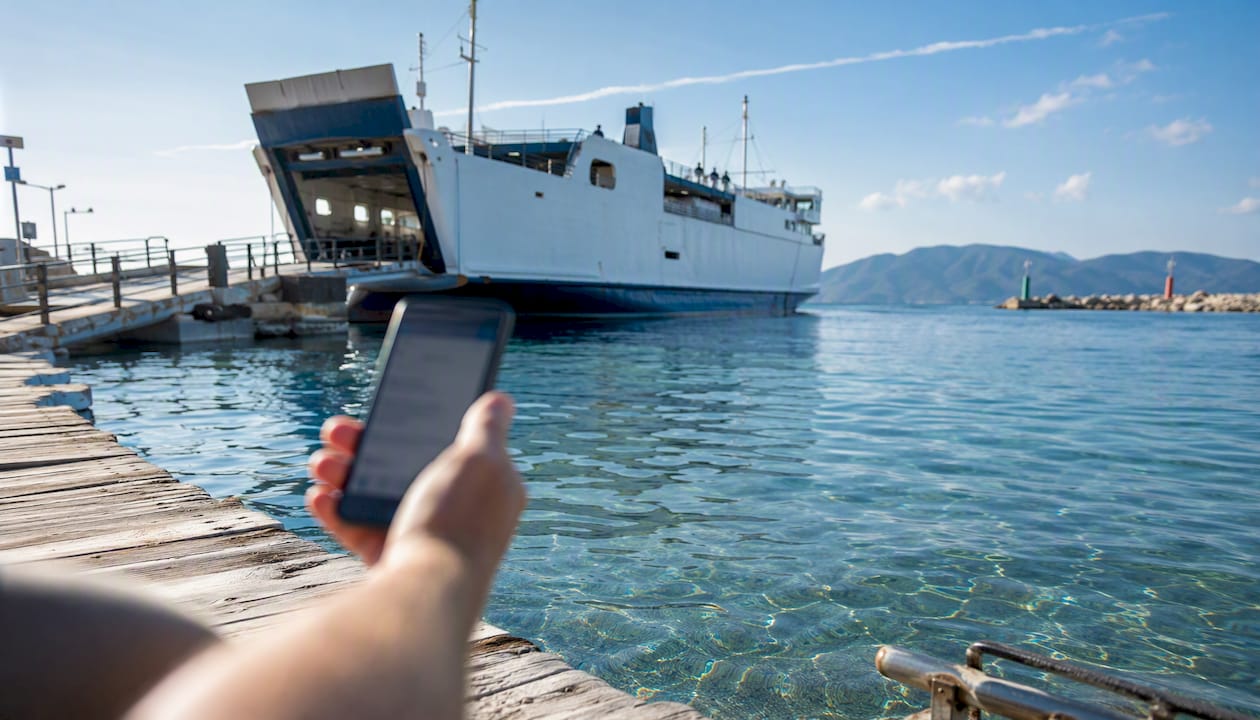 Molo dei traghetti affacciato su un mare cristallino mentre prenoti comodamente dal tuo smartphone
