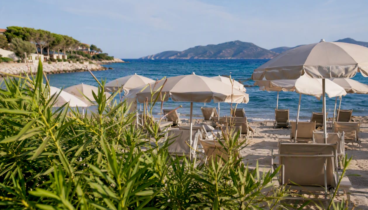 File di eleganti ombrelloni colorati che punteggiano la spiaggia dorata di uno stabilimento balneare italiano.