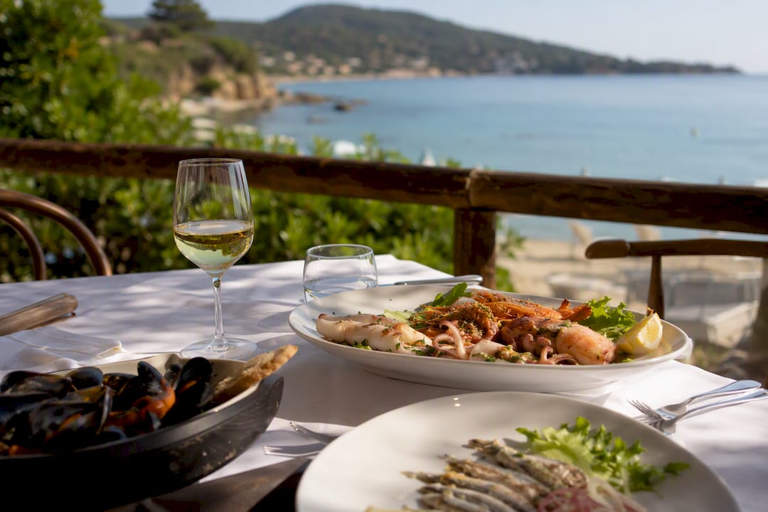 Un tavolo rustico sulla terrazza di un hotel, imbandito con un piatto di pesce fresco.